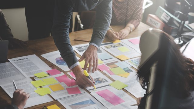 People around a boardroom table, looking at documents